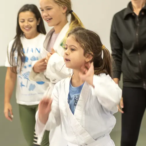 Mãe e filha de kimono no tatame, durante uma aula aberta a famílias.