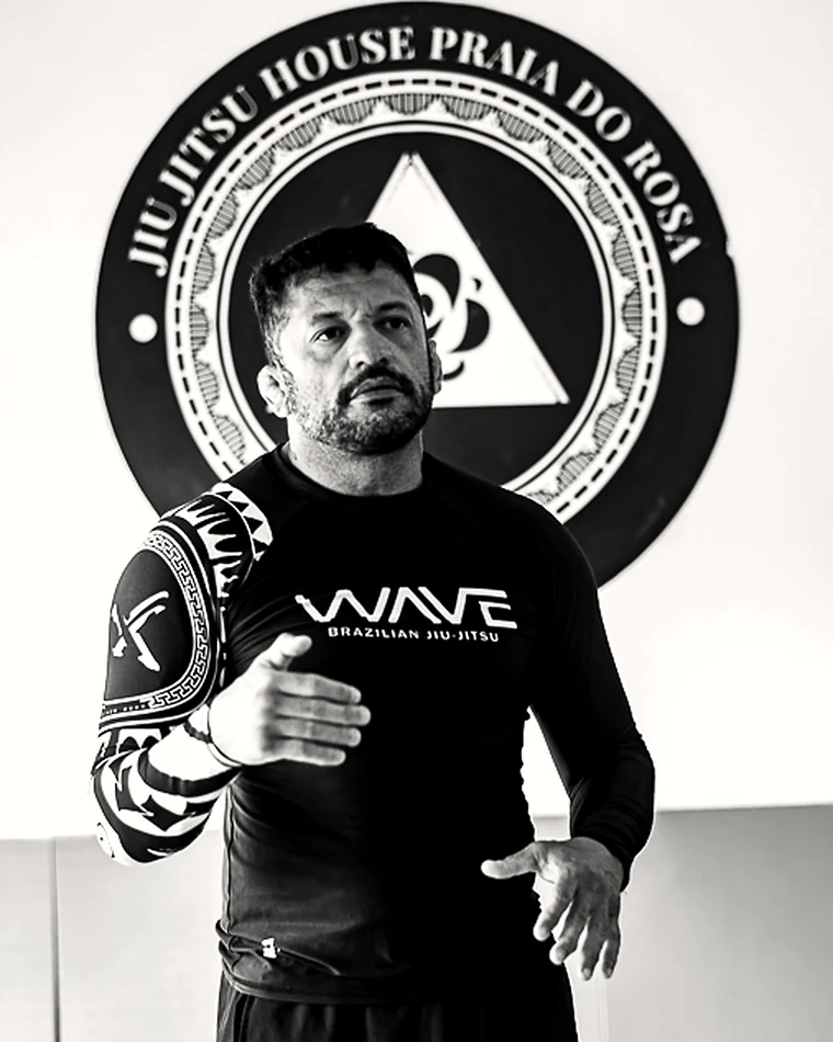 Retrato de Rodrigo Klippel, fundador e head coach da Jitshouse, diante do selo da casa.